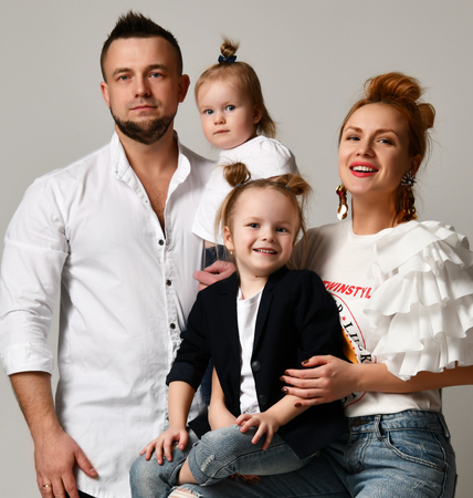 Happy family mother father and two daughter girls  smiling on gray studio backgroundの写真素材