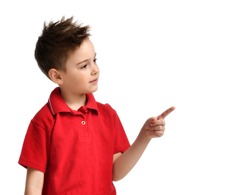 Young boy kid in red polo t-shirt pointing one finger at the corner isolated on white backgroundの写真素材