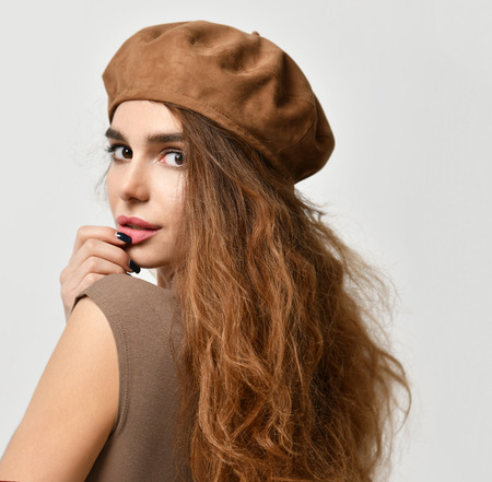 Young sexy brunette woman in brown beret hat looking at the corner  on gray backgroundの写真素材