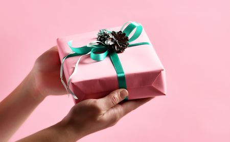 Woman hands give Christmas present gift  for new year 2019 on light pink backgroundの写真素材