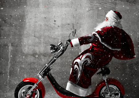 Santa Claus ride electric motorcycle bicycle scooter with bag full of presents and text copy space. New year and Merry Christmas and happy holidays conceptの写真素材