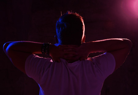 Neon light portrait of sexy man muscular body and white t-shirt looking up on darkの写真素材