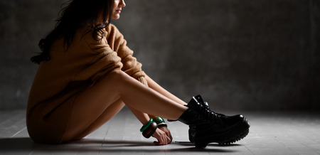 Young sexy blonde fashion woman sitting on floor in sexy knitted blouse on dark night  light...