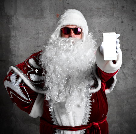 Santa Claus show white blank screen with text space of mobile cellphone. New year and Merry Christmas and happy holidays conceptの写真素材
