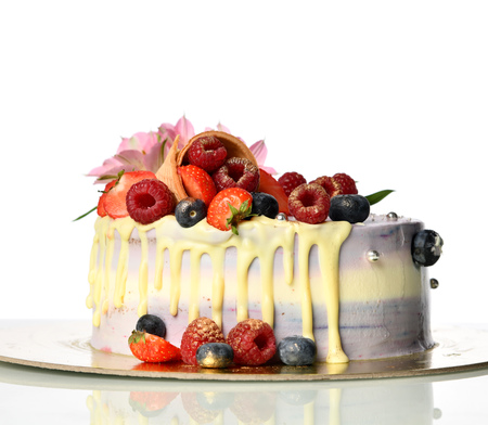 Delicious raspberry cake with fresh strawberries raspberries blueberry waffle and fresh flowers isolated on white backgroundの写真素材