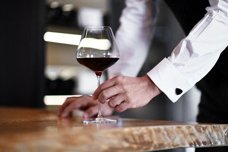 Man with glass of red wine on wooden table in restaurantの写真素材