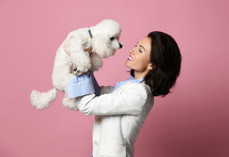 Beautiful woman hugging her lovely white poodle dog puppy on pink background happy smilingの写真素材