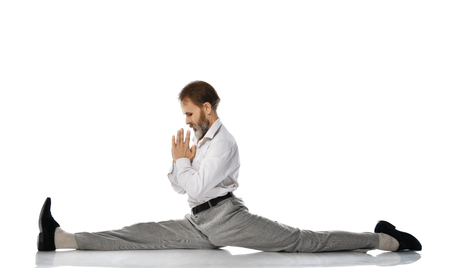 Old man practicing yoga classic asana pose do the splits against white backgroundの写真素材