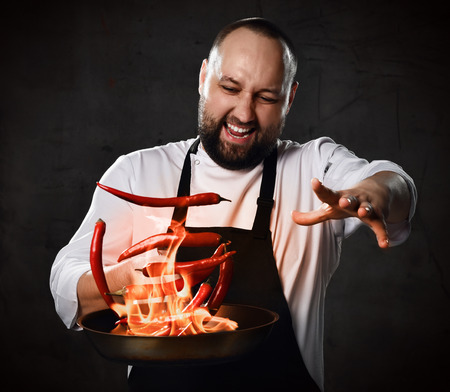 Professional chef prepares the dish with flame stirring in a frying pan on kitchen of the restaurant.の写真素材