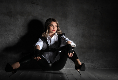 Young sensual mature beautiful sexy woman posing in white man shirt and high-heeled shoes on dark backgroundの写真素材