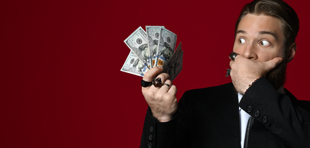 Business man hand holding American dollars  hundreds banknotes scary close mouth with hand on redの写真素材