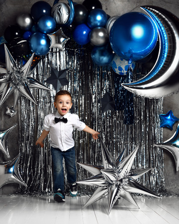Happy little boy with silver and blue metallic  moon balloons for birthday space party with free text spaceの写真素材