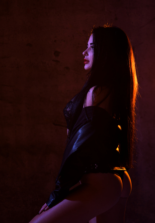 Beautiful sexy brunette woman posing in underwear in dark neon light backgroundの写真素材