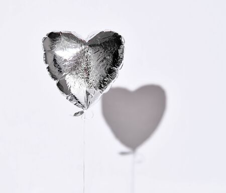 Party is over deflated silver heart balloon object for birthday party or love valentines day on white gray background with shadowの写真素材