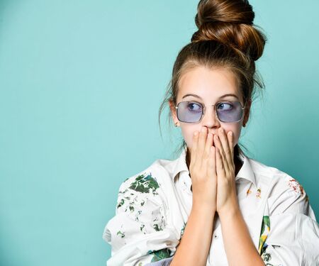Surprised young woman teenager girl in white shirt with paint stains is covering her mouth with...
