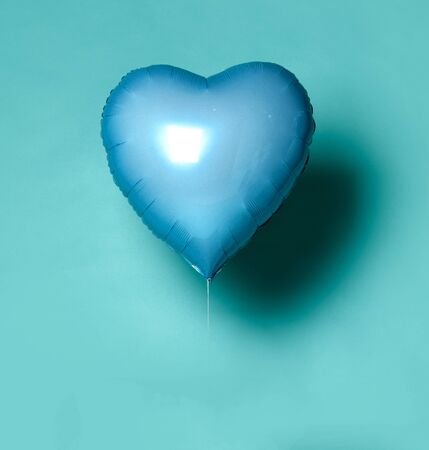 Single light blue big metallic heart balloon object for birthday on light blue mint backgroundの写真素材