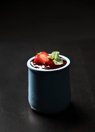 Strawberry and mint desert of fresh ripe  homemade yogurt pana cotta in blue jar on dark background. Healthy food conceptの写真素材
