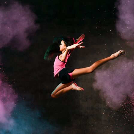 Street dance girl dancer jumping up dancing in neon light doing gymnastic exercises in studio on...