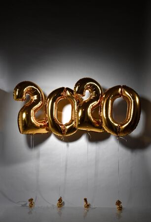 New year and christmas 2020 celebration concept. Gold foil balloons numeral 2020 on dark grey...