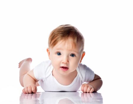 Infant child baby boy kid with blue eyes happy smiling screaming lying on a floor isolated on a white background. Closeup portraitの写真素材
