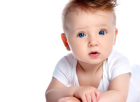 Infant child baby boy kid with blue eyes happy smiling screaming lying on a floor isolated on a whiteの写真素材