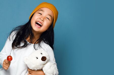Asian girl kid hold polar bear toy and lollipop candy happy smiling screaming. International day of polar bear concept.の写真素材