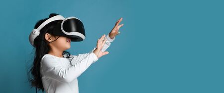 Young girl kid child play virtual reality game hold  vr glasses pointing hands. Cyber space and...