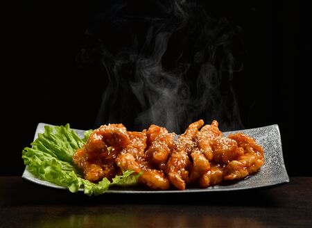 Hot and spicy bbq chicken wings strips with with green salad leaf and steam smoke on black backgroundの写真素材