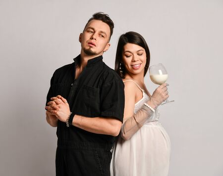 Portrait of young happy smiling beautiful wife and husband standing together and holding glass of...