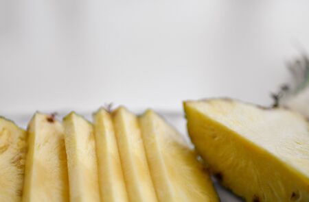 Closeup of freshly halved and sliced juicy pineapple on background with free text copy space at the...