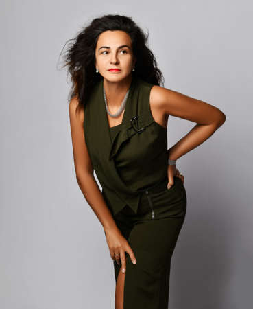 Millennial brunette latin woman with long curly hair in trendy outfit posing on white studio...