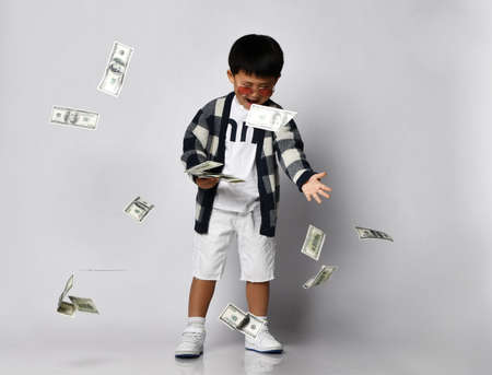 Happy screaming self-confident asian rich kid boy millionaire in sunglasses, plaid cardigan and...