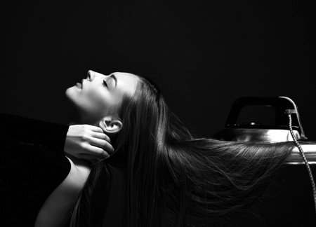 Black and white portrait of beautiful woman posing with eyes closed and her long silky straight hair under iron on boardの写真素材