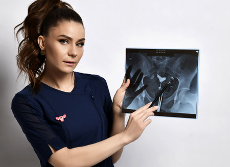 Young smiling brunette woman doctor gynecologist in blue dress standing and showing ultrasound shot...