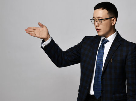 Portrait of asian businessman expert analyst in official suit, tie and glasses showing direction with his handの写真素材