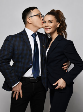 Young couple man and woman in love business professionals office workers in formal suits hug each other and kissingの写真素材