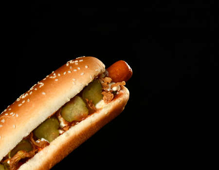 Hot dog in which sausage, mustard, ketchup, pickle cucumbers on black backgroundの写真素材