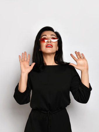 Adult good looking pretty woman in stylish casual black dress stands holding hands up gesturing wait signの写真素材