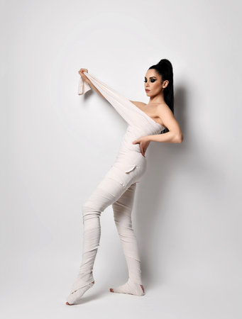 Young slim woman massage therapist, cosmetologist in medical bandages, body wrap stands holding pulling the end of bandの写真素材