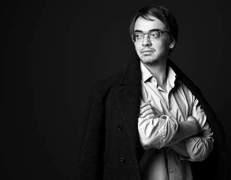 Black and white. Strong self-confident adult man in white shirt and teed jacket on shoulders standing with arms crossedの写真素材