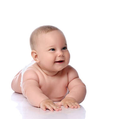 Happy infant child baby girl kid in diaper is lying on her tummy, stomach, crawling, laughing and...