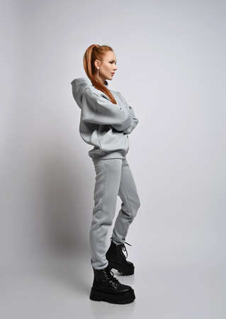Young fashionable woman in sports suit and brutal shoes stands sideways and looking straight ahead at copy spaceの写真素材