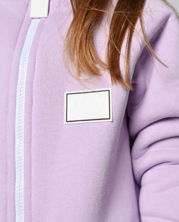 Closeup of red-haired kid girl in pink jacket with zipper and blank rectangular patch. Chest, sleeveの写真素材