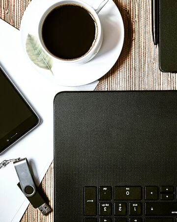 Laptop, notebook, coffee and flash card on wooden background.の写真素材