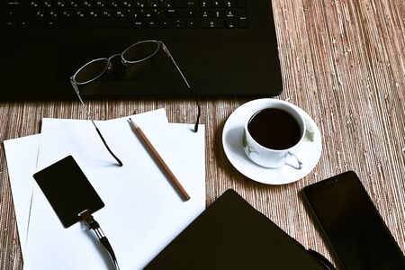 Laptop, notebook, coffee, smartphone and glasses on wooden background. White paper and pencil. Flat...