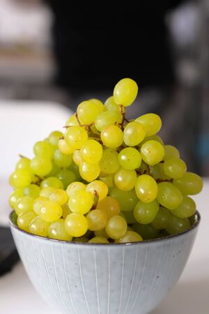Green grapes in a bowl on the white table. Grapevine, healthy.の写真素材