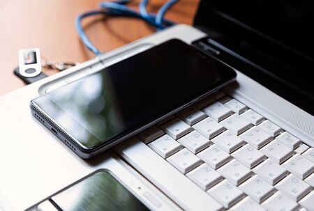 Blue internet cable, flash card and smartphone laying on the white laptop keyboard. Top angle view, workplace concept.の写真素材