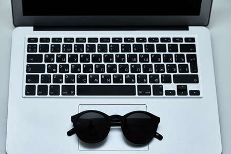 Stylish minimalistic workplace with laptop keyboard, sunglasses in flat lay style. White background. Top view.の写真素材