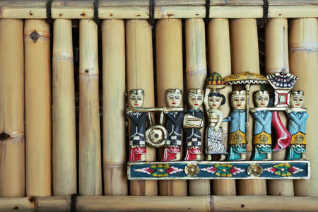 Colored balinese people figures during hindu ceremony on the bamboo wall