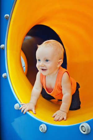 Smiling boy crawling through the playground tubeの写真素材